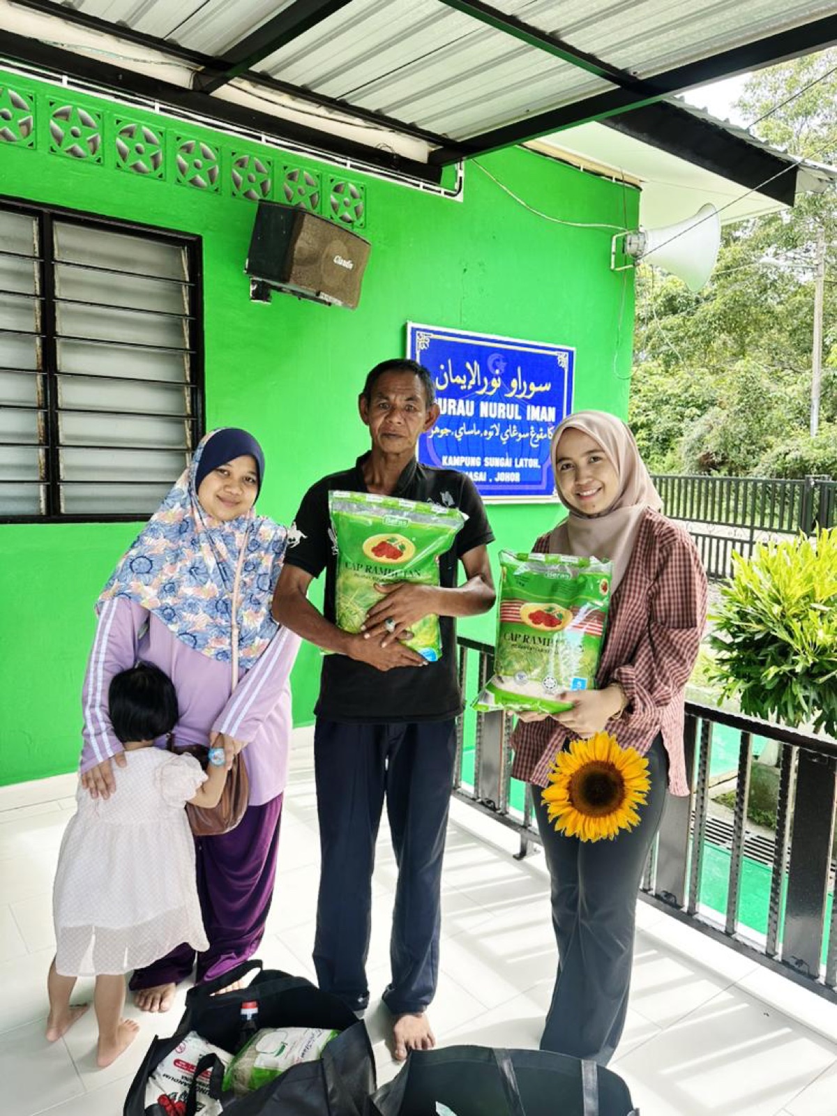 Mediwira volunteers handing rice to a family at Surau Nurul Iman, Kampung Sungai Latoh