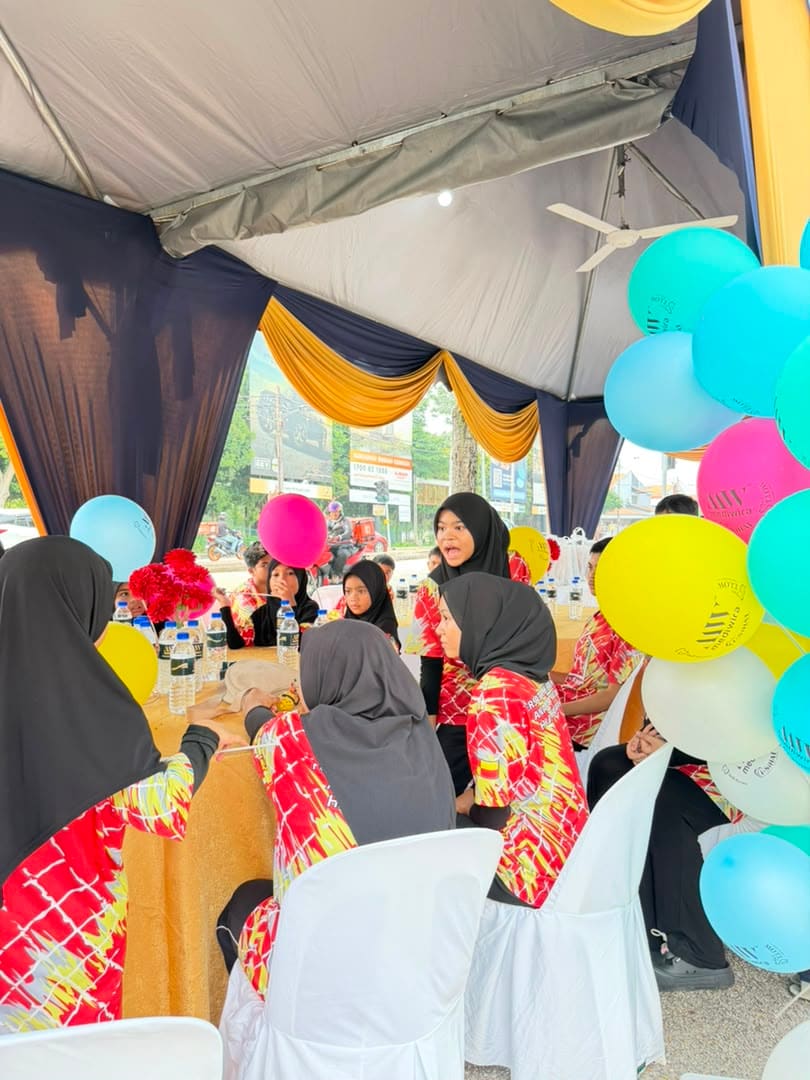 Children and guests seated at a balloon-decorated table under the marquee