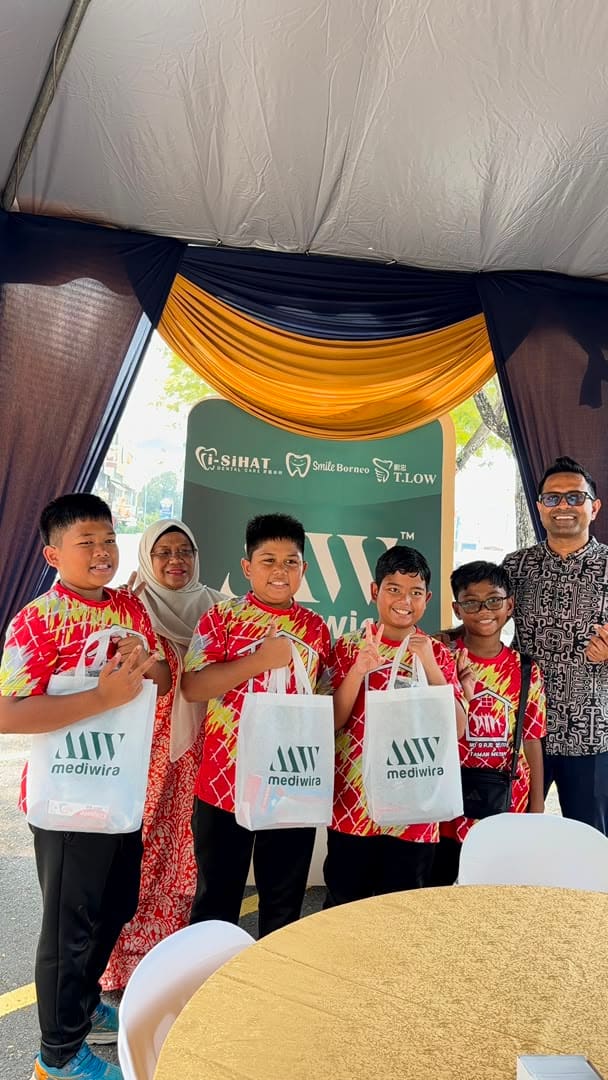Children and a guardian posing with their Mediwira tote bags at the anniversary backdrop