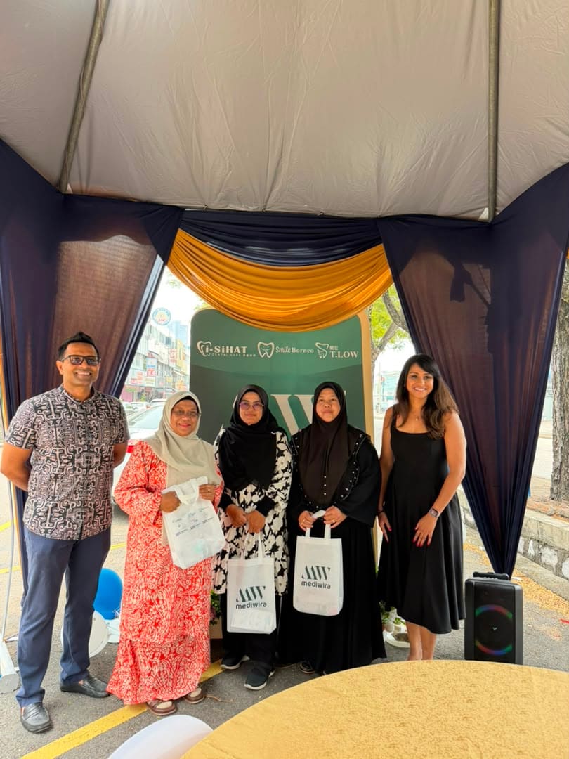 Guests in traditional dress posing with their Mediwira tote bags at the backdrop