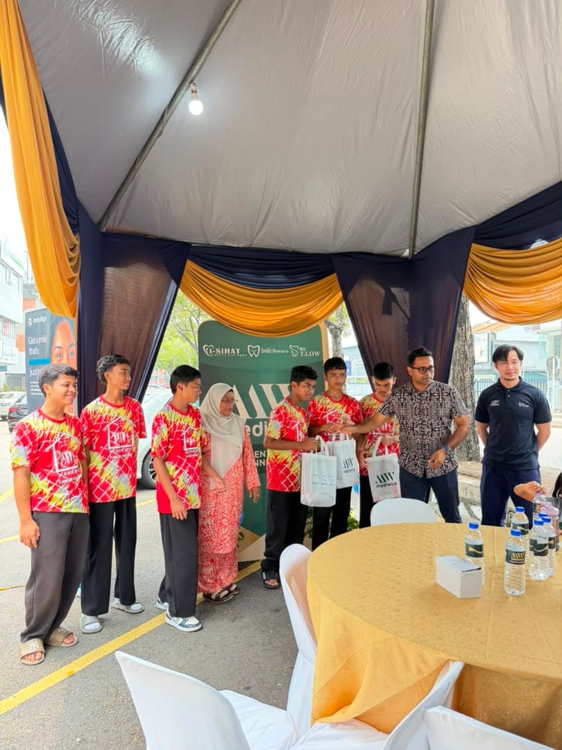 A group of boys with the clinic’s team, holding their tote bags at the backdrop
